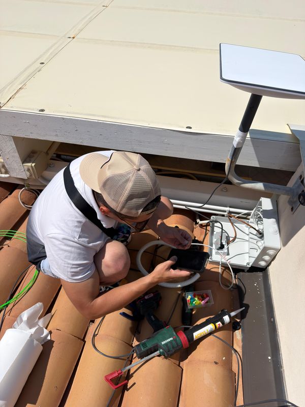 Tecnico installa l'antenna Starlink e il quadro stagno su un tetto in tegole in Calabria