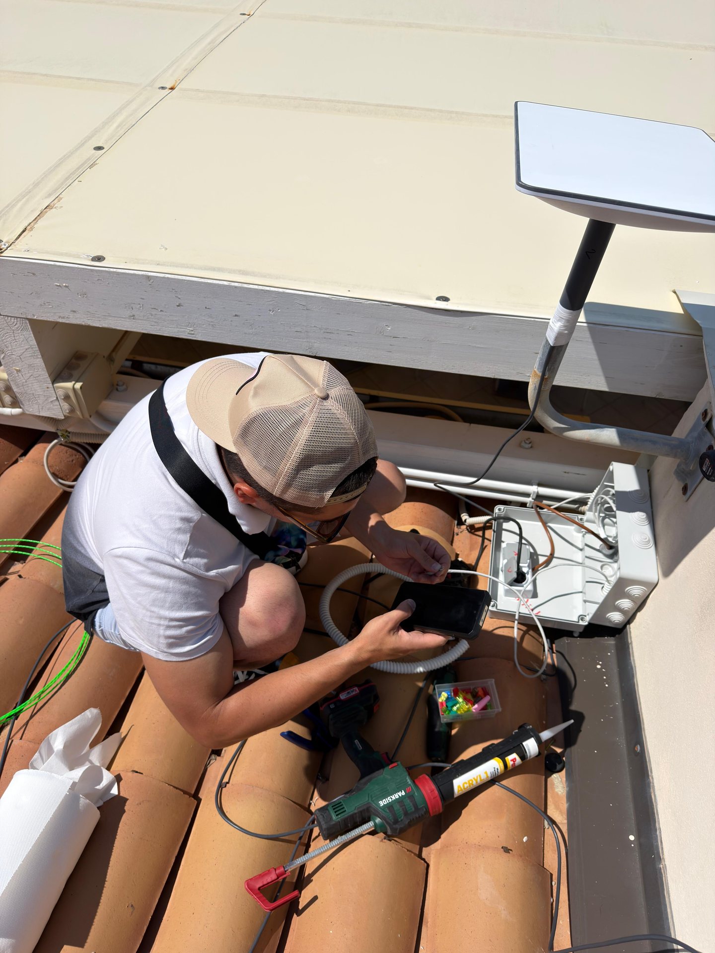 Tecnico installa l'antenna Starlink e il quadro stagno su un tetto in tegole in Calabria